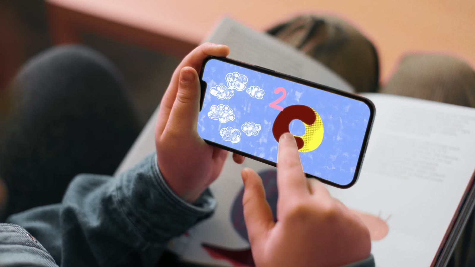 Sur un téléphone, l'application du livre affiche une énigme : six nuages, la lettre C et le chiffre 2.