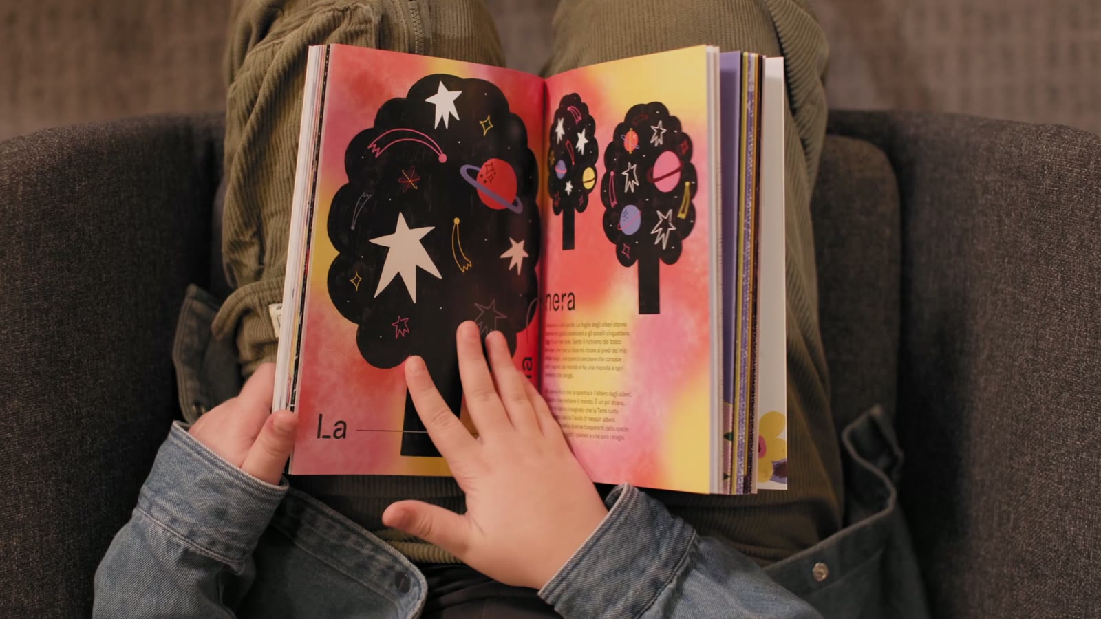 Le livre ouvert sur une double page illustrée : un arbre noir rempli d'étoiles sur un fond rose et jaune.