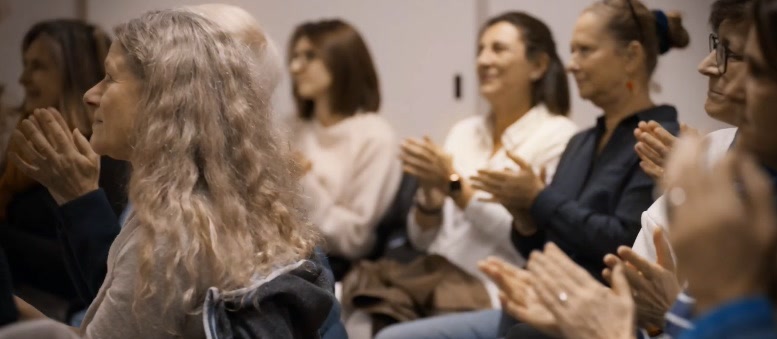 Un public d'adultes applaudit à la fin d'une conférence.